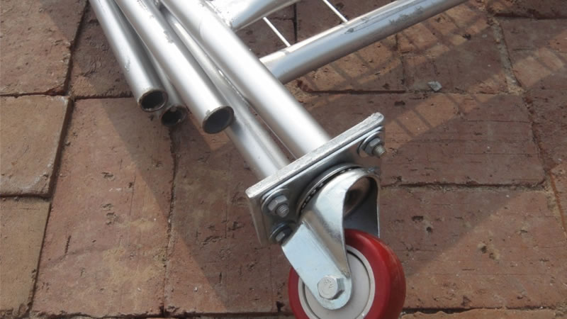The corner of temporary fence panels, which lying on the ground. One of these panels is installed a red rubber wheel.